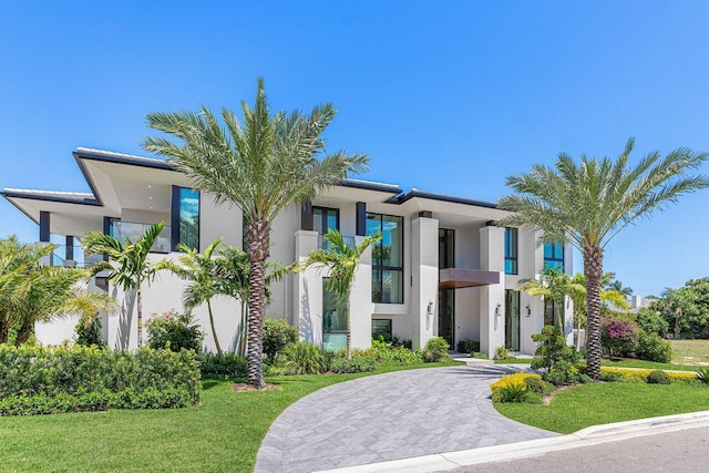 modern home with stucco siding, a front lawn, and curved driveway