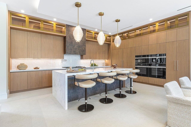 kitchen featuring modern cabinets, backsplash, light floors, a kitchen bar, and a center island with sink