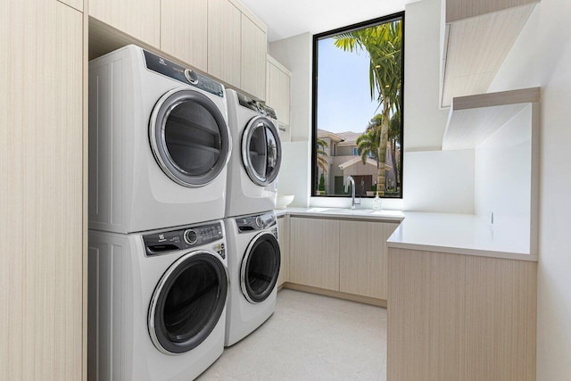 clothes washing area with stacked washer / drying machine and cabinet space