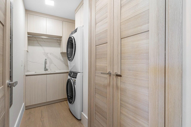washroom with stacked washing machine and dryer and light wood-type flooring