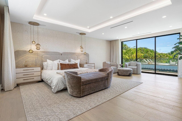 bedroom featuring access to outside, a wall of windows, wood finished floors, a raised ceiling, and recessed lighting
