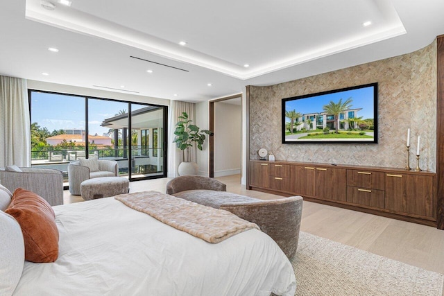 bedroom with access to exterior, light wood finished floors, recessed lighting, and a raised ceiling