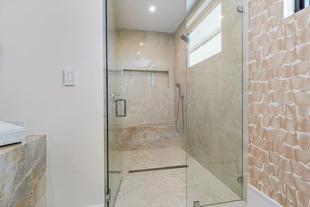 full bathroom with a marble finish shower and baseboards