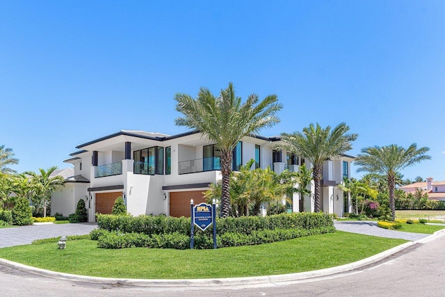 view of front of house with stucco siding, decorative driveway, a garage, and a front yard