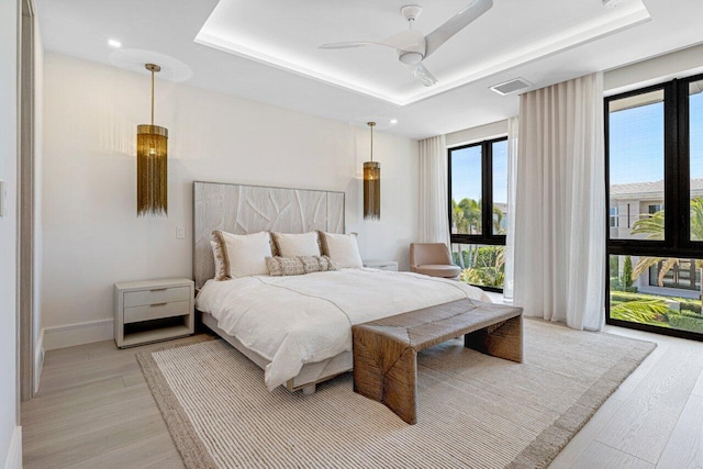 bedroom featuring a raised ceiling, access to outside, light wood-style floors, and ceiling fan
