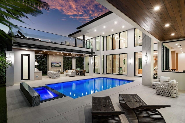rear view of property featuring an outdoor living space, a balcony, a patio area, and a pool with connected hot tub