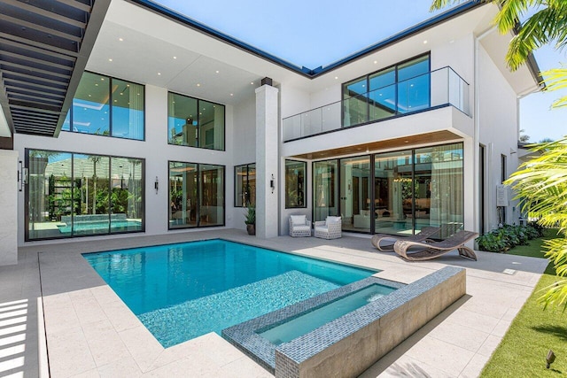 rear view of property with a balcony, a patio area, and stucco siding