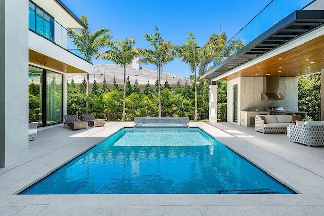 swimming pool with exterior kitchen, an outdoor hangout area, a patio area, and a grill