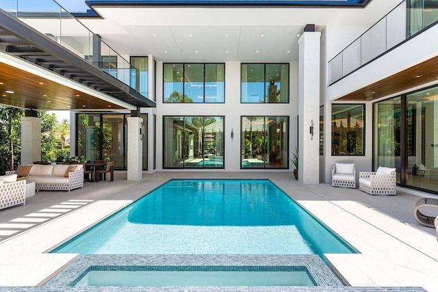 view of swimming pool featuring a patio area, a pool with connected hot tub, and an outdoor living space