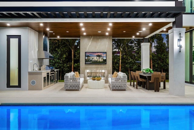outdoor pool featuring exterior kitchen, an outdoor hangout area, a patio, and grilling area