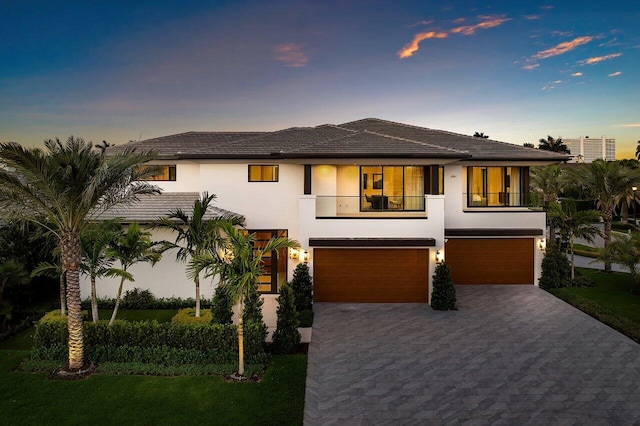 view of front of house with stucco siding, a balcony, an attached garage, and decorative driveway