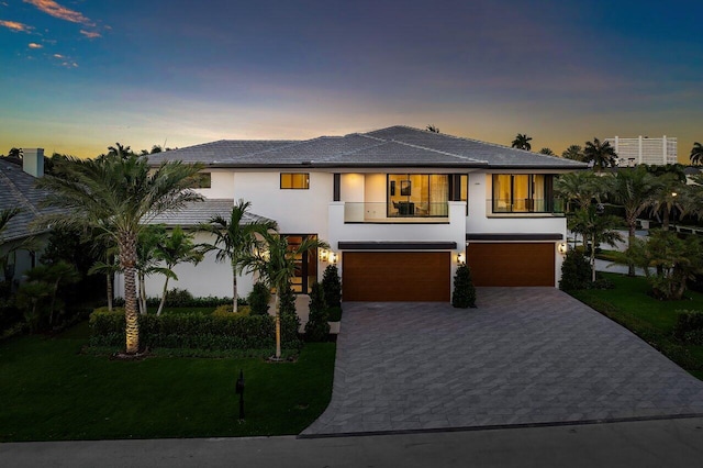 view of front facade with stucco siding, driveway, a lawn, and an attached garage