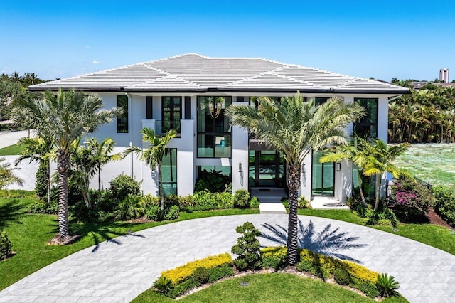 modern home featuring a tiled roof, stucco siding, and curved driveway