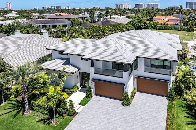 view of front of home with an attached garage, stucco siding, a tiled roof, and decorative driveway