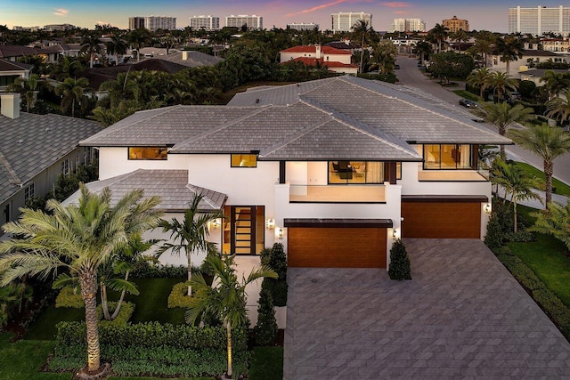 contemporary house featuring stucco siding, a garage, and decorative driveway