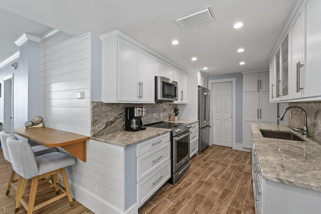 kitchen featuring high quality appliances, a sink, crown molding, recessed lighting, and decorative backsplash