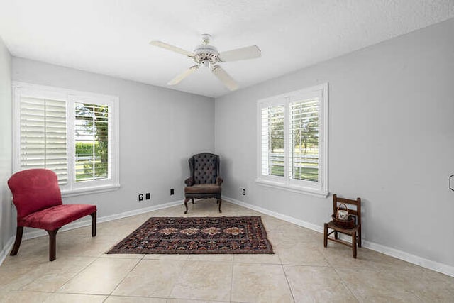 living area with baseboards, a ceiling fan, and light tile patterned flooring