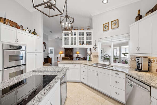 kitchen featuring crown molding, appliances with stainless steel finishes, tasteful backsplash, a sink, and a notable chandelier