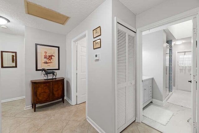 corridor with light tile patterned flooring, a textured ceiling, and baseboards