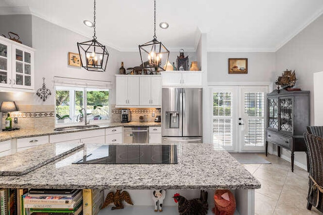 kitchen featuring crown molding, appliances with stainless steel finishes, tasteful backsplash, a sink, and a notable chandelier