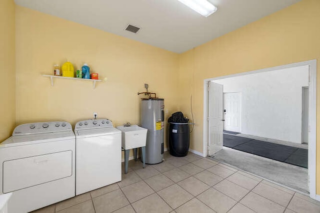 clothes washing area with laundry area, independent washer and dryer, visible vents, light tile patterned floors, and electric water heater