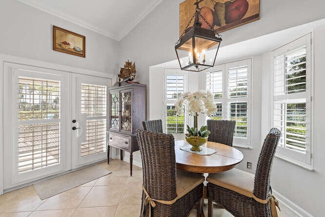 dining area featuring crown molding, a chandelier, french doors, light tile patterned floors, and lofted ceiling