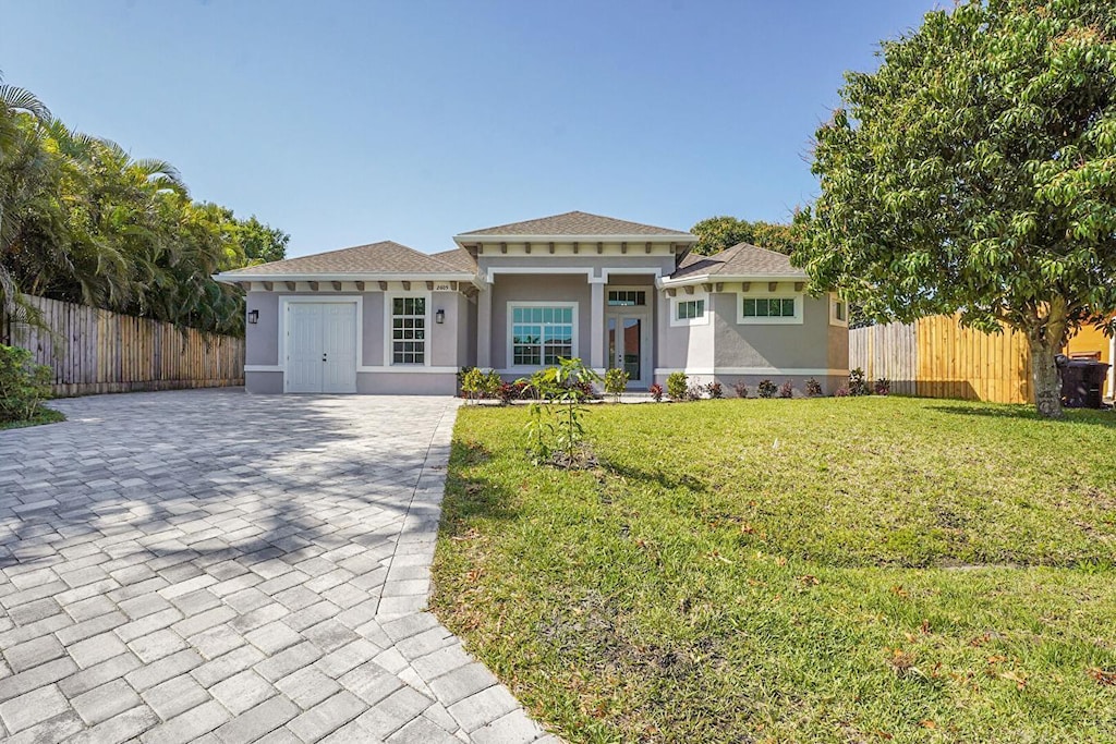 2605 SW Acco Rd, Port Saint Lucie, FL 34953 - view of front facade featuring fence, stucco siding, driveway, and a front lawn