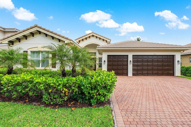 11952 Fox Hill Cir, Boynton Beach, FL 33473 - mediterranean / spanish-style house featuring decorative driveway, an attached garage, a tiled roof, and stucco siding