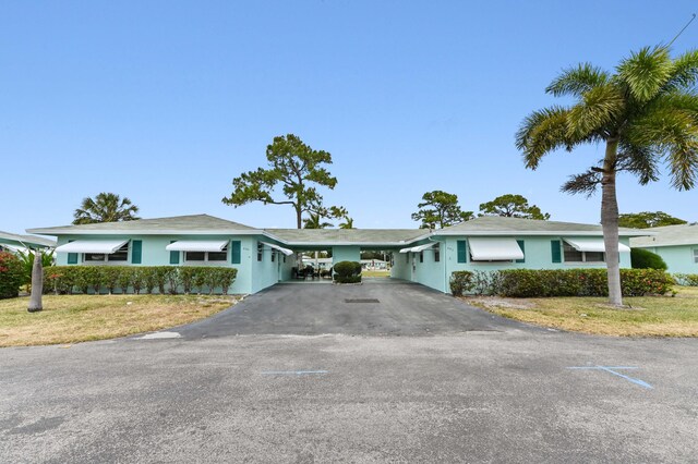 single story home featuring a front lawn, aphalt driveway, stucco siding, and a carport