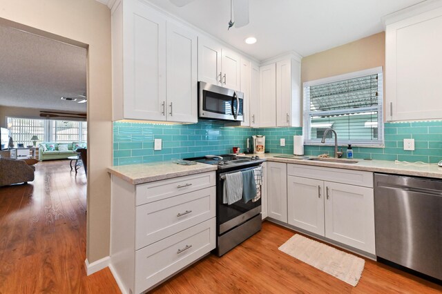 kitchen featuring stainless steel appliances, a ceiling fan, white cabinetry, and light wood-style flooring