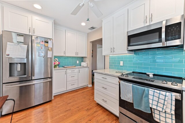kitchen with appliances with stainless steel finishes, tasteful backsplash, light wood finished floors, and white cabinetry