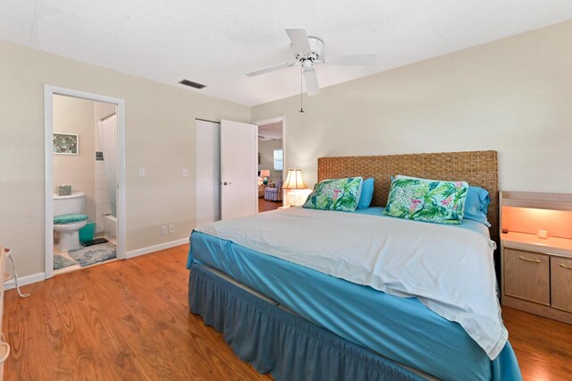 bedroom featuring visible vents, wood finished floors, baseboards, ensuite bathroom, and a ceiling fan