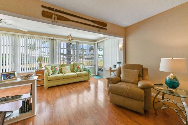 living area with baseboards, ceiling fan, and wood finished floors