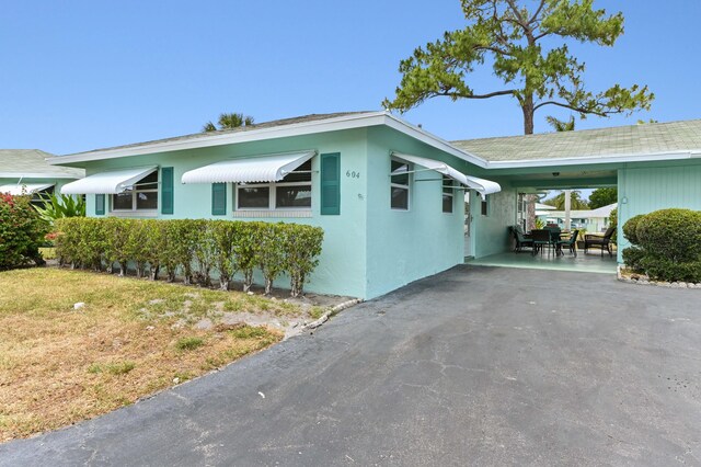 view of front of house featuring stucco siding, driveway, and an attached carport