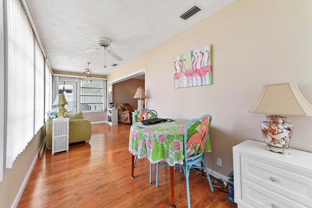 dining space with baseboards, ceiling fan, wood finished floors, and visible vents