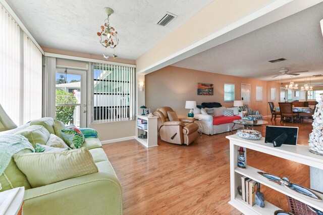 living area featuring a notable chandelier, baseboards, visible vents, and light wood-style flooring