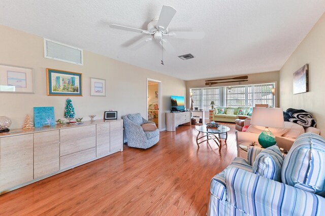 living room with visible vents, light wood-style flooring, and ceiling fan