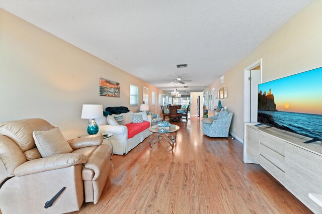living room with ceiling fan, visible vents, and light wood finished floors