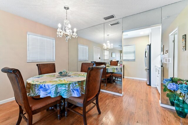 dining area with baseboards, light wood-style flooring, and a notable chandelier