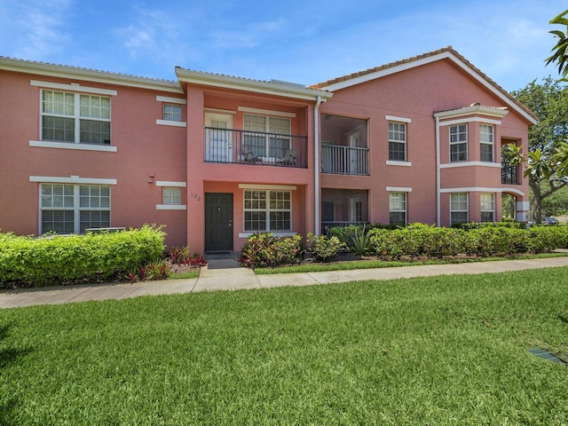 multi unit property with a tiled roof, stucco siding, and a front lawn