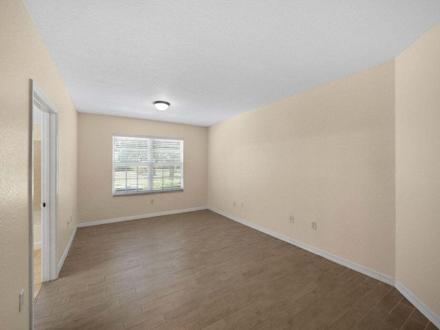 spare room with baseboards, a textured ceiling, and wood finished floors