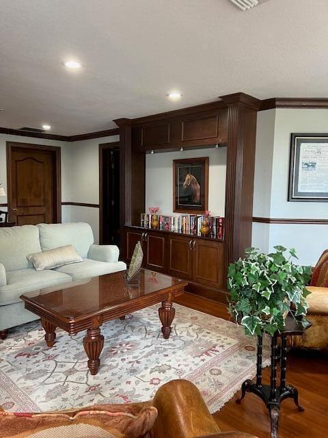 living room featuring crown molding, recessed lighting, and wood finished floors