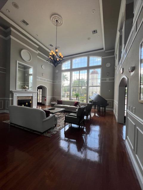 living area featuring a fireplace, a decorative wall, a chandelier, a towering ceiling, and visible vents