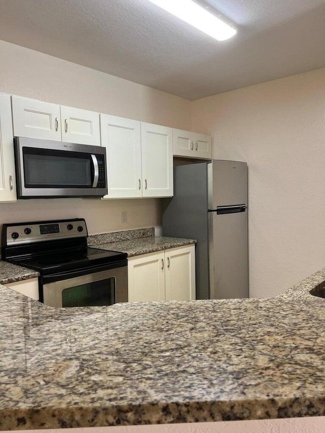 kitchen featuring dark stone counters, white cabinetry, and appliances with stainless steel finishes