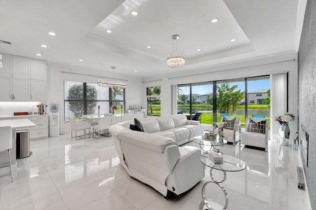 living area with a tray ceiling, an inviting chandelier, recessed lighting, and light tile patterned flooring