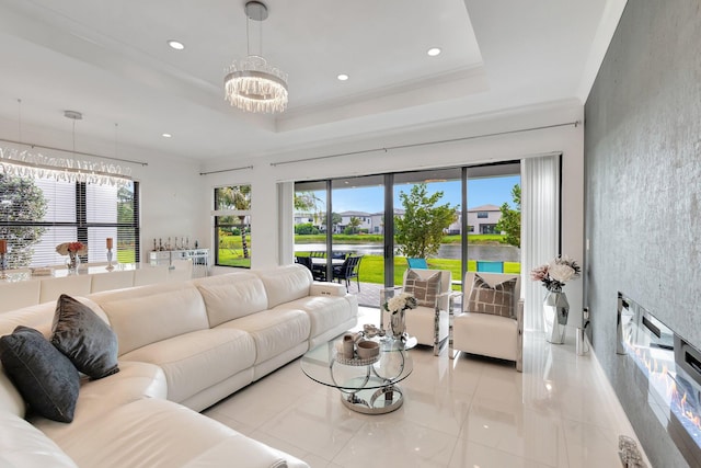 living area featuring a water view, a chandelier, a raised ceiling, and a healthy amount of sunlight
