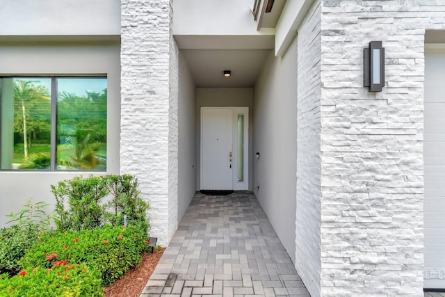 view of exterior entry with stucco siding and stone siding