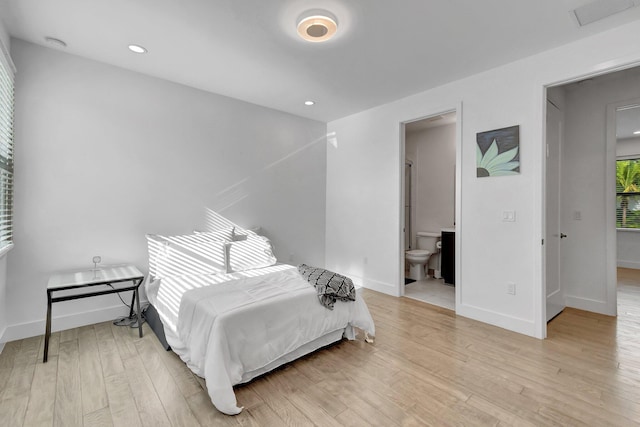 bedroom featuring connected bathroom, visible vents, baseboards, light wood-style floors, and recessed lighting