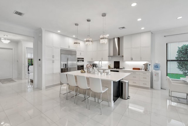 kitchen with recessed lighting, visible vents, wall chimney exhaust hood, light countertops, and appliances with stainless steel finishes