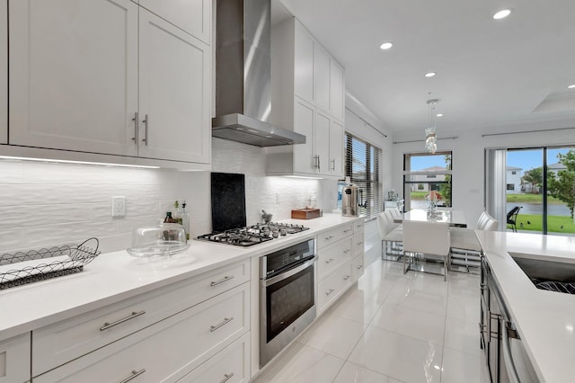 kitchen featuring light tile patterned floors, wall chimney exhaust hood, appliances with stainless steel finishes, decorative backsplash, and recessed lighting